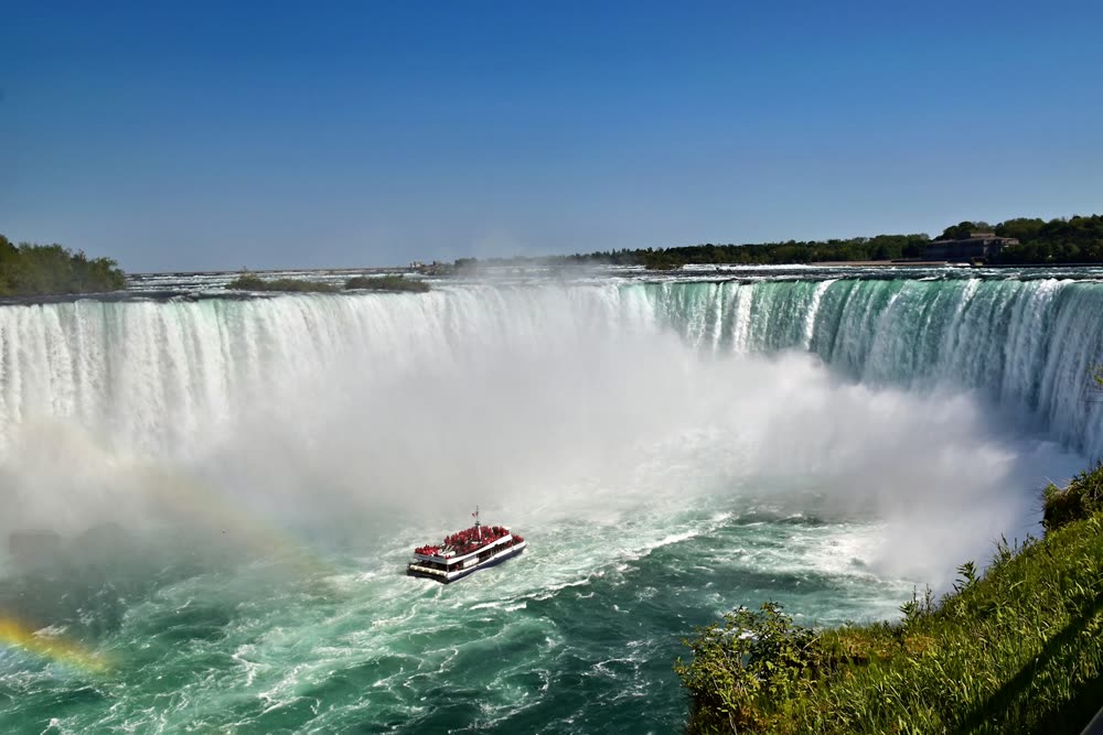 Niagara Falls tour boat sailing into the mist below Horseshoe Falls on a sunny day