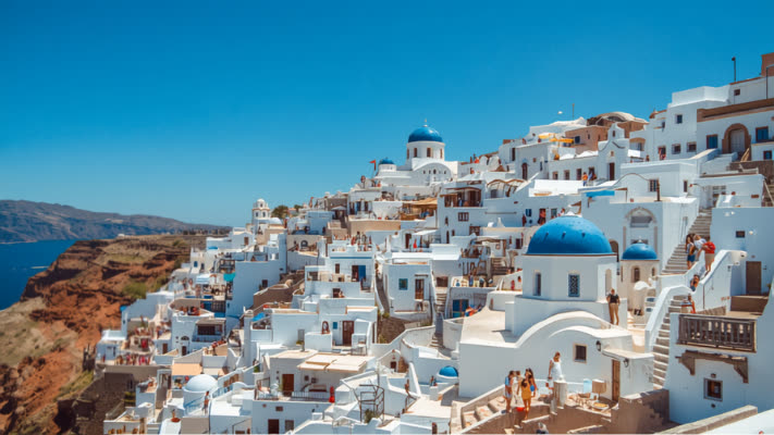 Santorini whitewashed buildings and blue-domed churches overlooking the sea on a sunny day